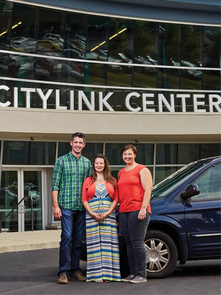 Tracy Summers (center) stands in front of her Chrysler Town & Country with Changing Gears founder Joel Bokelman and program director Katie Frazier.